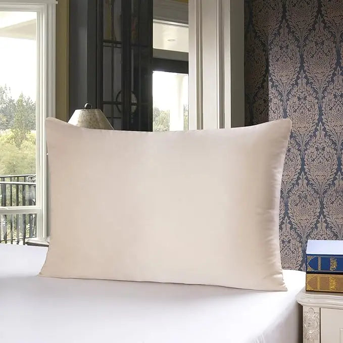 Beige pillow on a bed with a decorative wall and window in the background