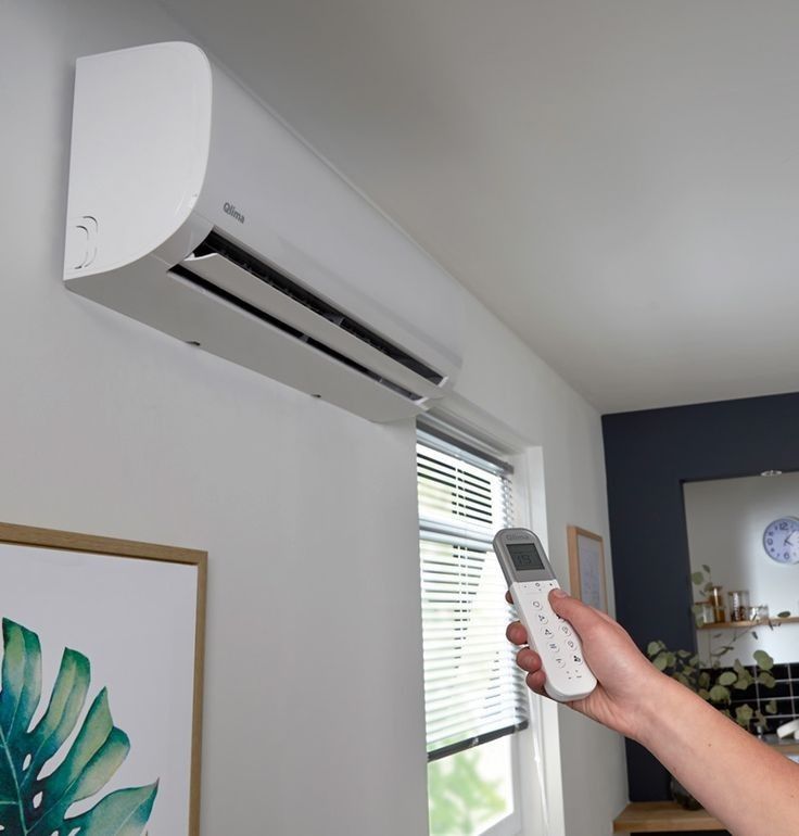 Wall mounted air conditioner heater unit installed on bedroom wall with remote control